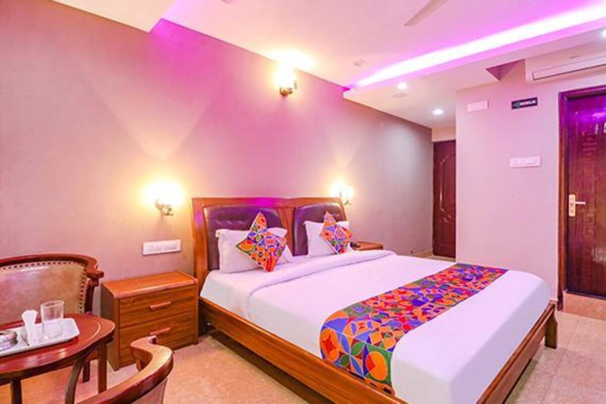 A hotel room with a bed, bedside tables, a wooden chair, a small table with a tray, and a door.
