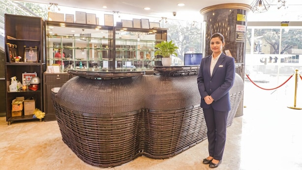 A reception area with a curved counter, a potted plant, and a security camera. - Fabhotel Turning Point (Bengaluru)