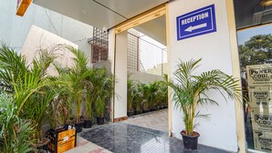 A reception area with a sign indicating the direction to the reception, potted plants, and a concrete floor. - Fabhotel Easy Nest (Bengaluru)