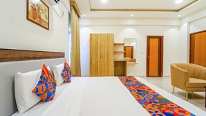 A hotel room with a bed, a chair, a wooden cabinet, and a door. - Fabhotel Easy Nest (Bengaluru)