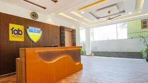 A hotel reception area with a wooden reception desk, a clock, and a sign for 'Fab Hotels Easy West'. - Fabhotel Easy Nest (Bengaluru)