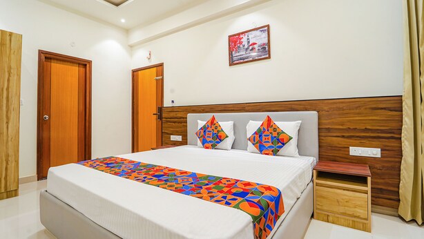 A hotel room with a large bed, wooden headboard, two bedside tables, and a wall-mounted picture. - Fabhotel Easy Nest (Bengaluru)