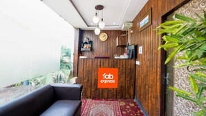 A reception area with a wooden wall, a clock, a reception desk, and a sofa. - Fabexpress Golden Stone (Ghaziabad)
