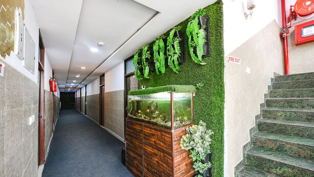 A hallway with a fire exit sign, a fish tank, and a staircase. - Fabexpress Golden Stone (Ghaziabad)