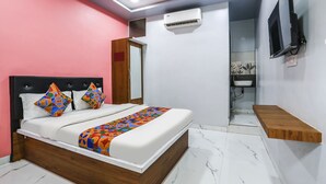 Een slaapkamer met een bed, een aan de muur bevestigde televisie en een houten plank.