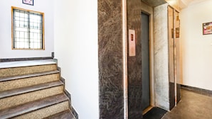A staircase with a marble wall and an elevator. - Fabexpress India Gate (Chennai)