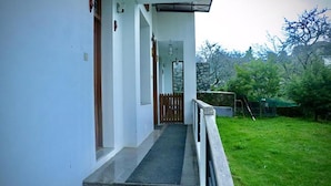 A house with a covered porch, a small front yard, and a wooden fence. - Fabhotel Prime D Grand (Kodaikanal)