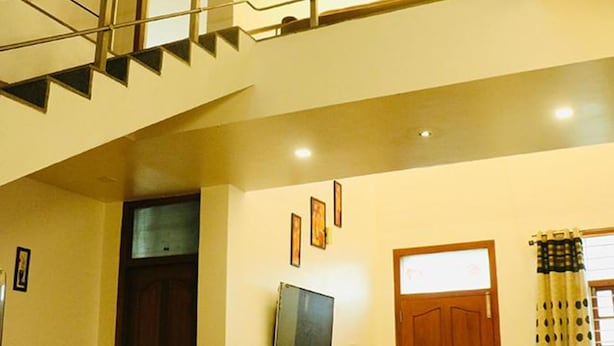 A staircase leading to an upper floor, a door with a frosted glass panel, and a television on a stand. - Fabhotel Prime D Grand (Kodaikanal)