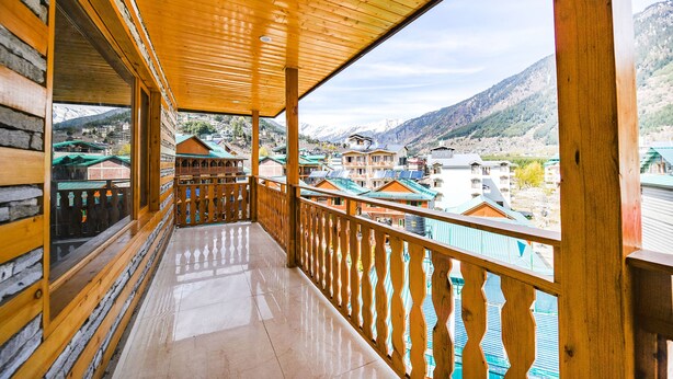 Uma varanda de madeira com vista para uma aldeia montanhosa.