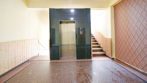 An elevator with a glass door, a staircase with wooden steps, and a tiled floor. - Fabhotel Prime The Kalinga Grand (Manali)