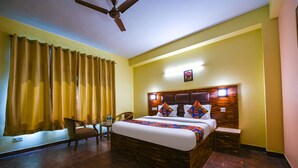 A hotel room with a wooden bed, a ceiling fan, a desk, and a chair. - Fabhotel Prime The Kalinga Grand (Manali)