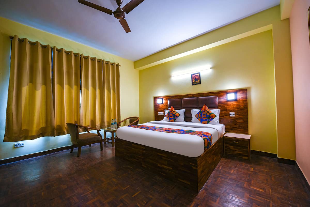 Une chambre d’hôtel avec un lit en bois, un ventilateur de plafond, un bureau et une chaise.