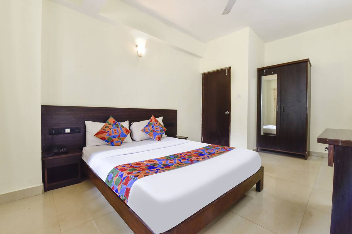A neatly made bed with a colorful bedspread, a wooden headboard, and two nightstands with a lamp on one.