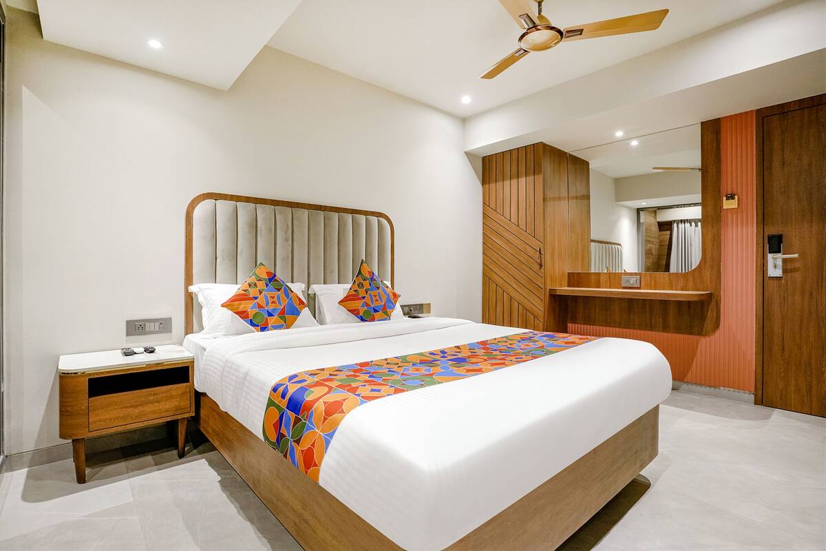 A modern bedroom with a large bed, a wooden nightstand, a ceiling fan, and a wooden wardrobe.