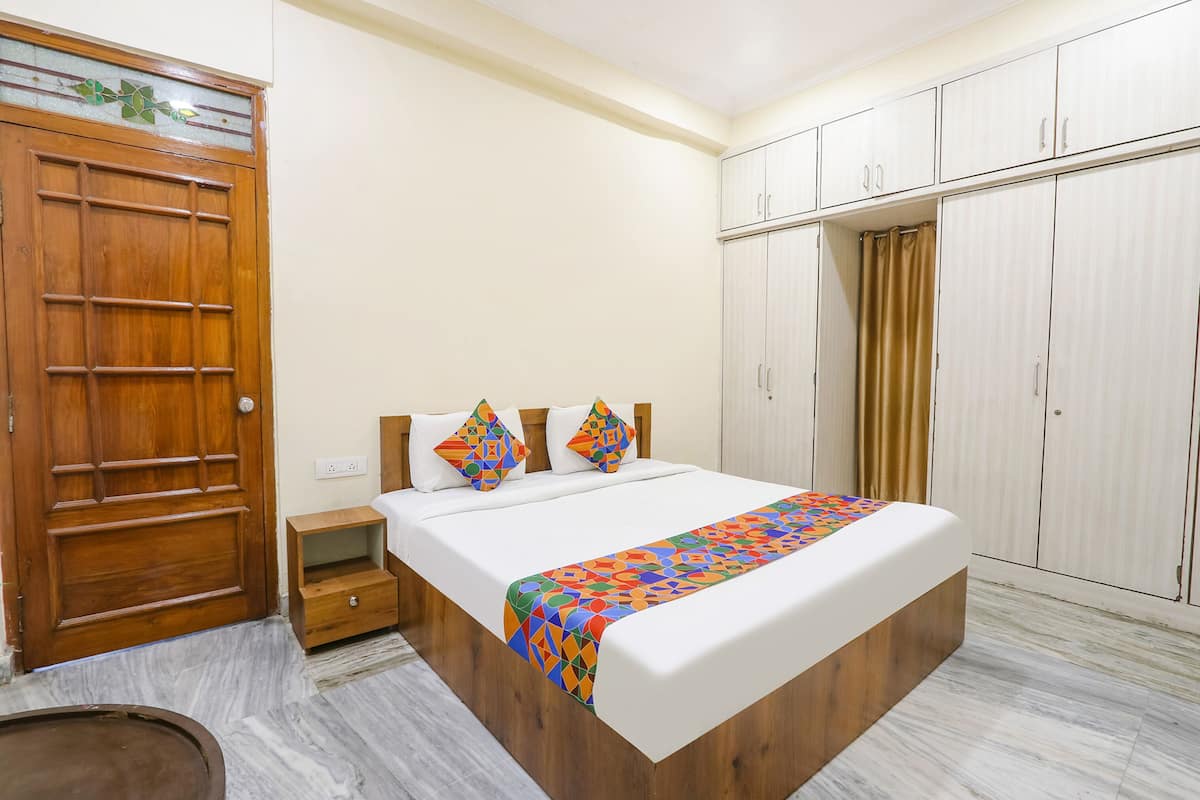 Un dormitorio con puerta de madera, una cama con manta colorida, una mesita de noche y un armario.
