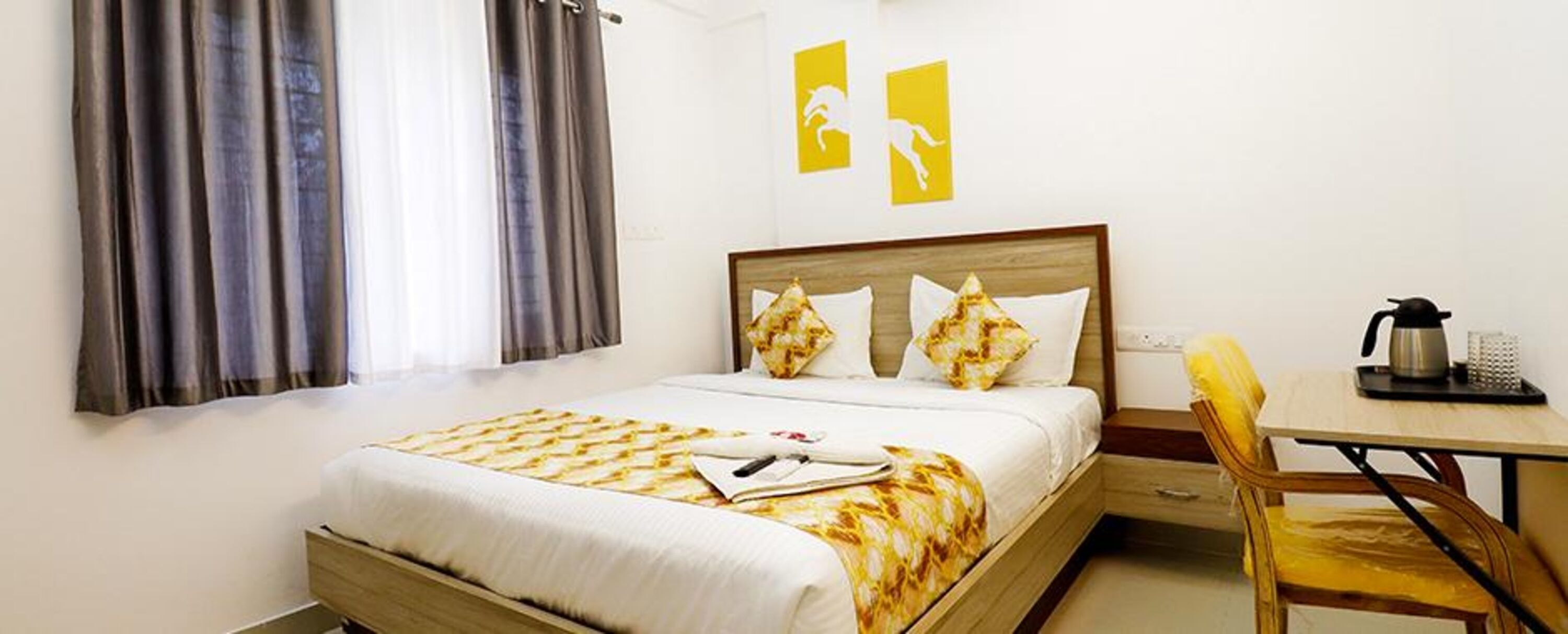 A hotel room with a bed, a desk, a chair, and a coffee maker.