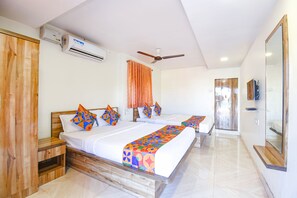 A hotel room with two beds, an air conditioning unit, a ceiling fan, a shower area, and a large mirror.