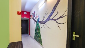 Un couloir orné d’une fresque représentant un arbre et un paon, avec une horloge et un panneau « Il est interdit de fumer ».