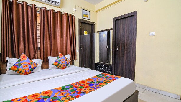 Une chambre d’hôtel avec un lit, des rideaux, un miroir et une porte.