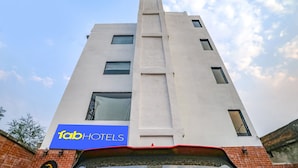 Een modern gebouw met een 'fabHOTELS' bord, met een opvallend verticaal element en meerdere ramen.