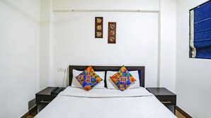 Een hotelkamer met een bed, twee nachtkastjes, een telefoon en twee decoraties aan de muur.