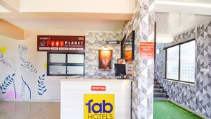 A reception desk with a sign for 'Fab Hotels' and a 'Food Planet' sign. - Fabexpress Prajakta Holiday Inn (Mahabaleshwar)