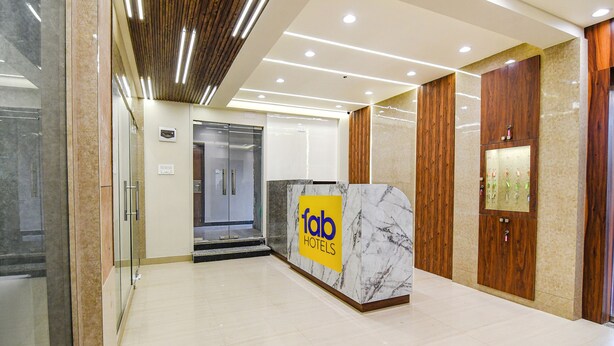 Een hotel receptie met een marmeren balie, houten lambrisering en een glazen lift.