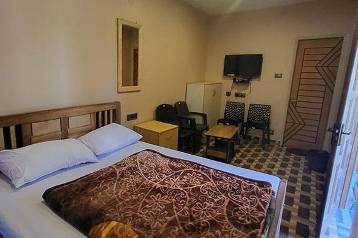 Une chambre à coucher comprenant un lit, un bureau, deux chaises, une télévision et une porte.