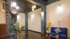 A lobby with a blue sofa, a clock, and patterned walls. - Fabhotel Dream Palace (Danapur)
