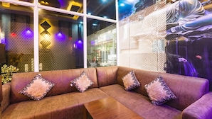 A modern interior with a leather sofa, patterned cushions, and a large Buddha statue. - Fabhotel Dream Palace (Danapur)