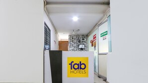 Una recepción con el logotipo de 'fab hotels', un ventilador de techo y un cartel que dice 'CAFETERÍA'.