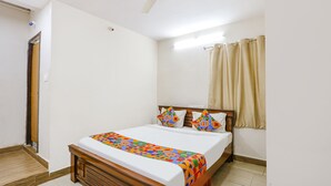 Un dormitorio con cama, ventilador de techo, ventana con cortinas y puerta.