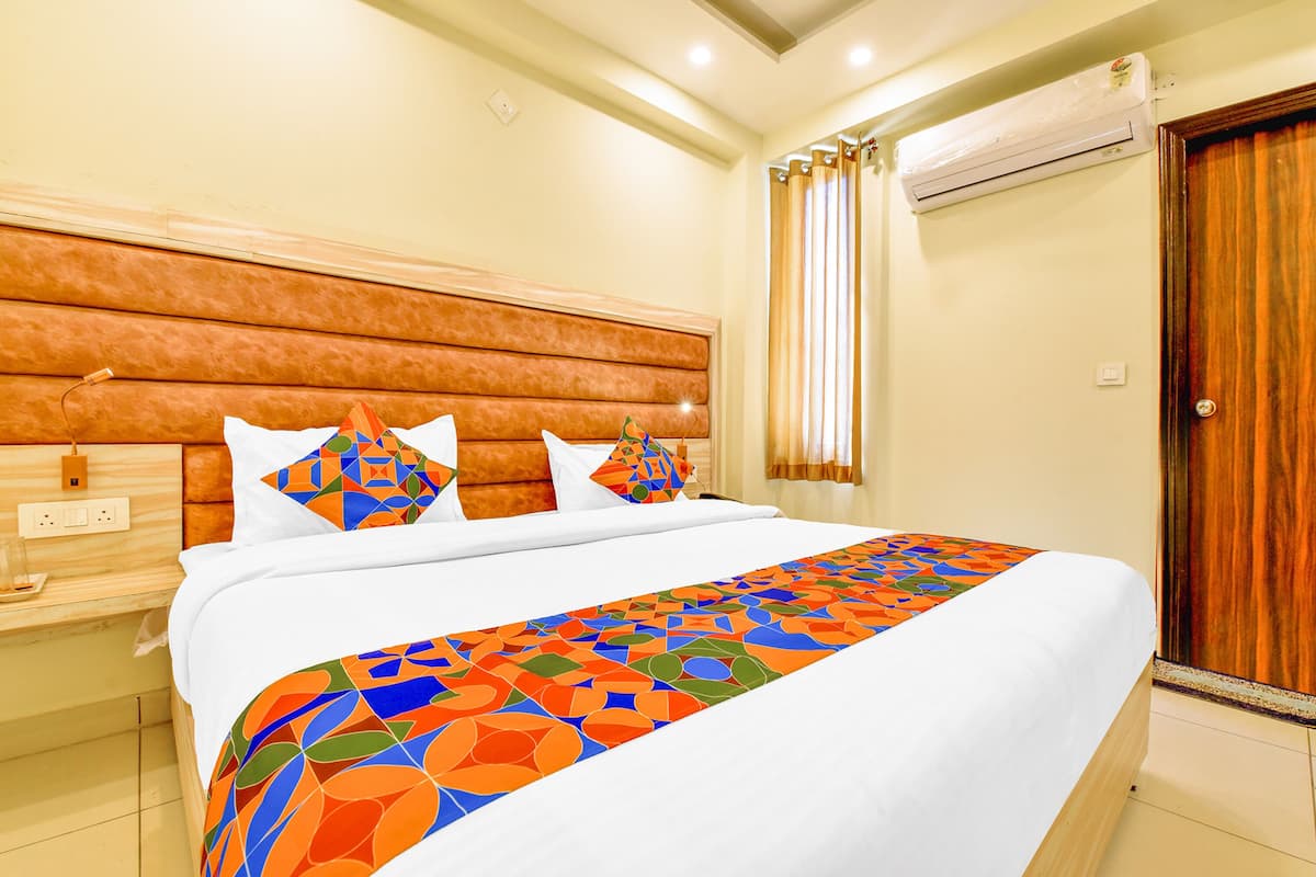 Quarto de hotel com uma cama grande, cabeceira de madeira, mesa de cabeceira e porta de madeira.