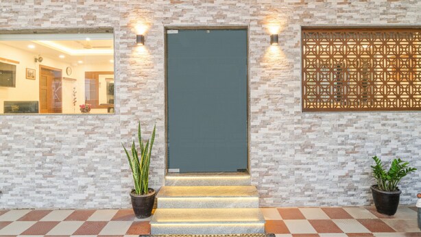 A hotel entrance with a stone-patterned wall, a dark door, and a decorative screen.