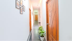 A hallway with wooden doors, framed artwork on the walls, and a potted plant.