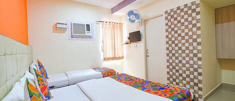 Habitación de hotel con dos camas, ventilador de techo, aire acondicionado, ventana con cortinas y diseño de pared a cuadros.