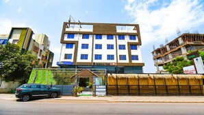 A multi-story hotel with a modern design, featuring a central entrance and a visible balcony on the upper floors.