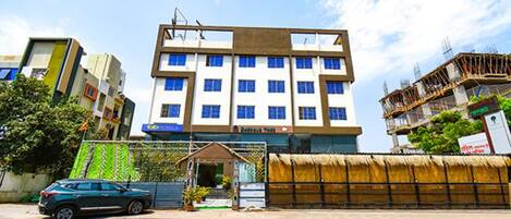 A multi-story hotel with a modern design, featuring a central entrance and a visible balcony on the upper floors.