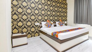 A modern hotel room with a large bed, a nightstand, and a patterned wallpaper.