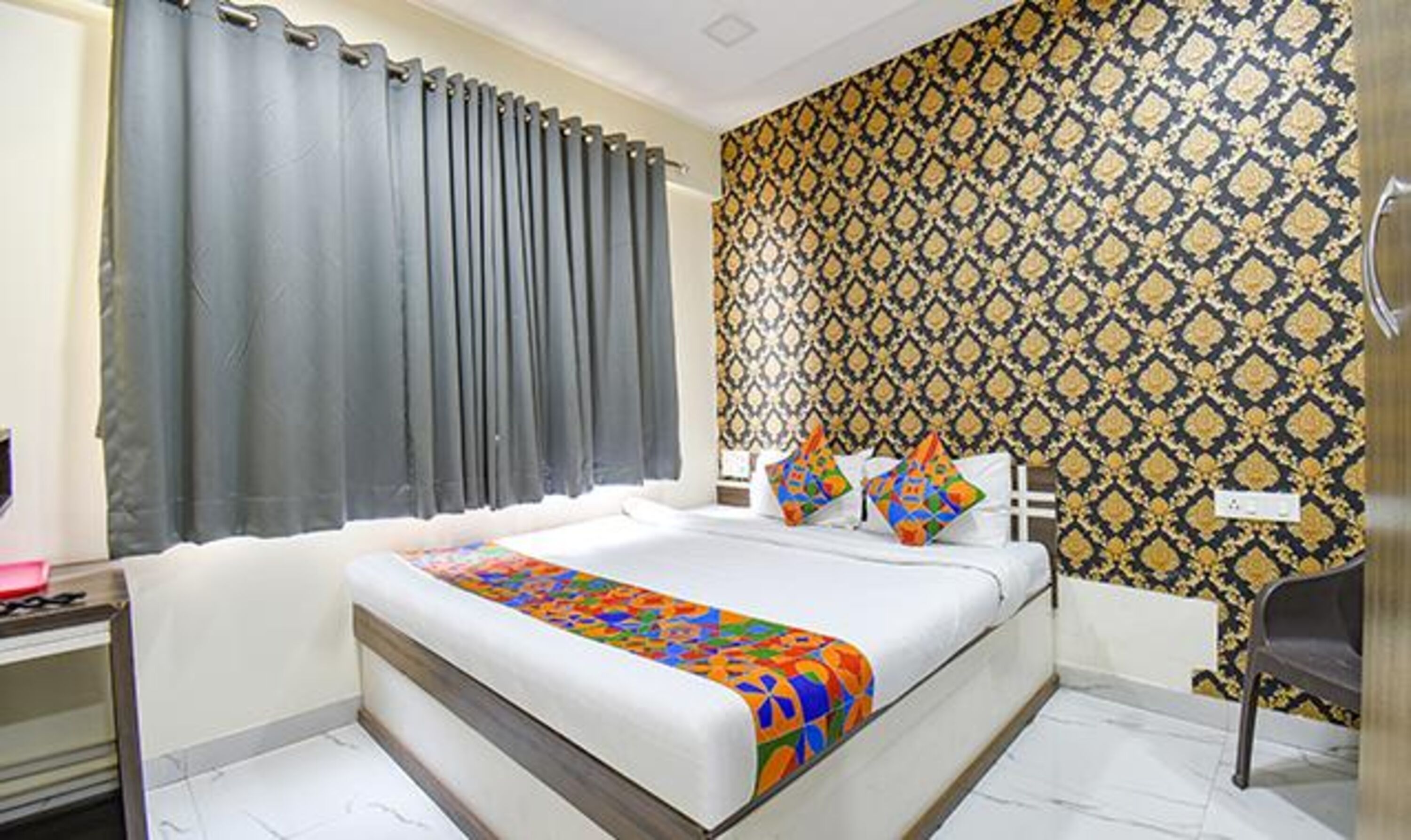 A bedroom with a bed, a chair, and a patterned wall.