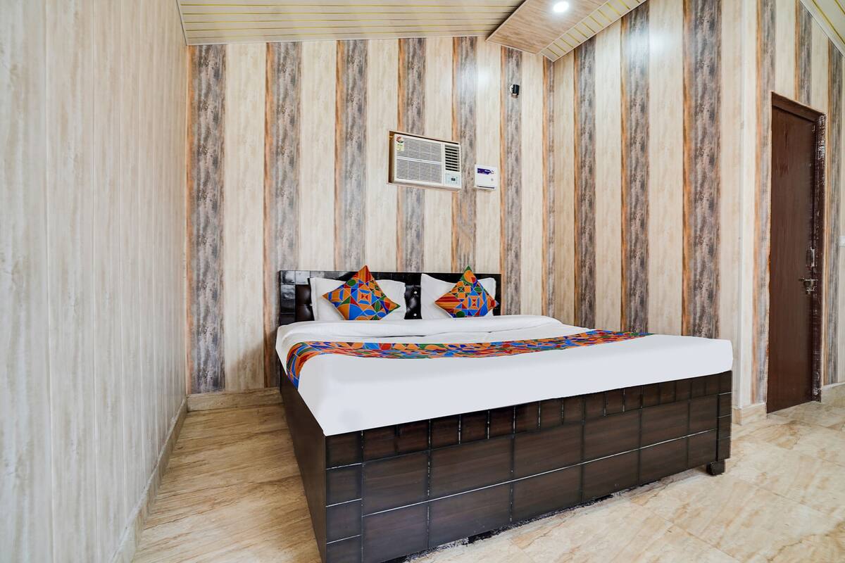 A bedroom with a bed, a wooden headboard, a patterned wall, and a door.