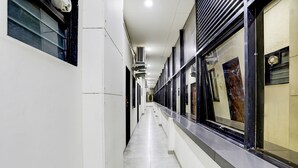 Corredor com aparelhos de ar condicionado, piso de azulejos e uma janela com um cartaz.