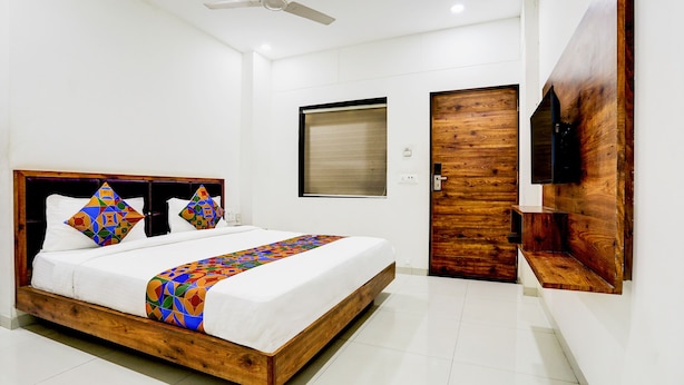 Quarto moderno com estrutura de cama de madeira, ventilador de teto, TV fixada na parede e porta de madeira.