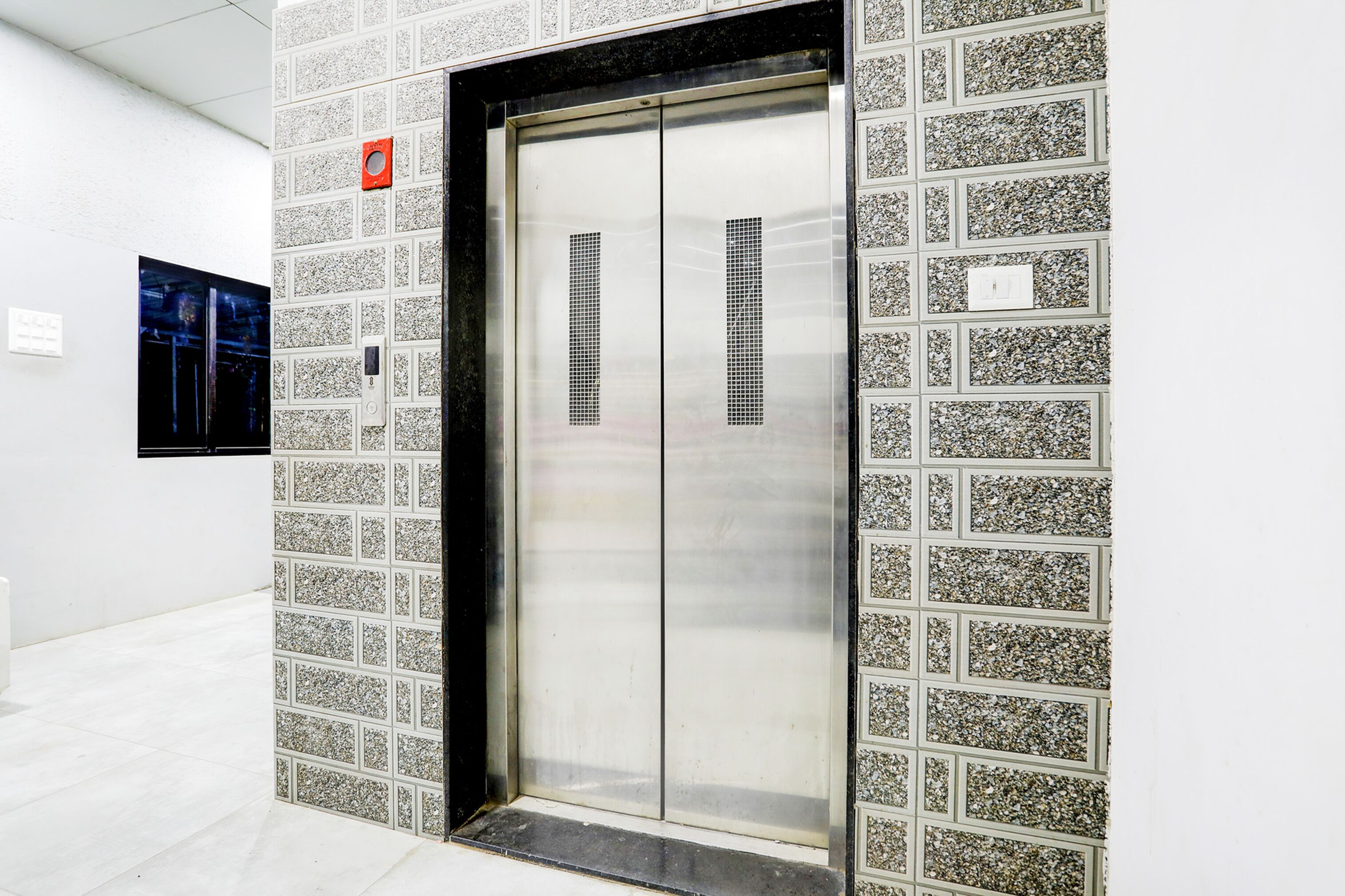 A modern elevator with a metallic finish, surrounded by a patterned wall.