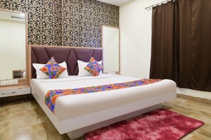Una cama bien tendida con una colcha estampada, cabecera y dos almohadas con diseños geométricos.