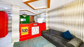 A reception area with a red desk, a sofa, and a patterned wall. - FabHotel PP Residency Tilak Nagar (New Delhi)