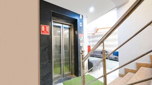 A hotel lobby with a fire extinguisher sign, an elevator, and a staircase. - FabHotel PP Residency Tilak Nagar (New Delhi)
