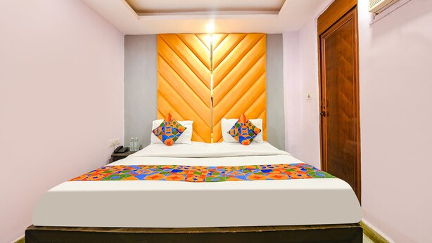 A neatly made bed with a patterned bedspread, a wooden headboard, and two decorative pillows. - FabHotel PP Residency Tilak Nagar (New Delhi)