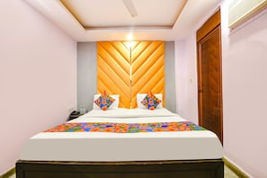 A neatly made bed with a patterned bedspread, a wooden headboard, and two decorative pillows. - FabHotel PP Residency Tilak Nagar (New Delhi)