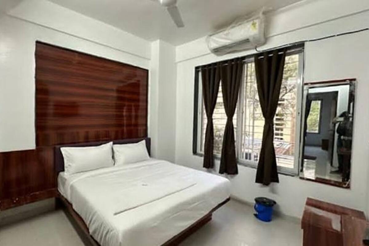 A bedroom with a bed, a wooden headboard, a window with curtains, and a ceiling fan.
